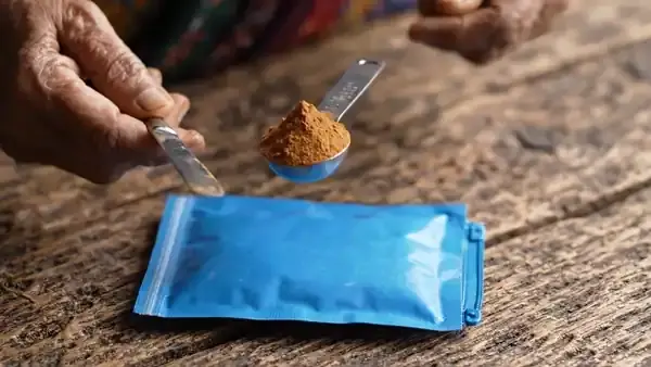 Half a teaspoon of pale powder levelled with the back of a butter knife over a plain blue pouch